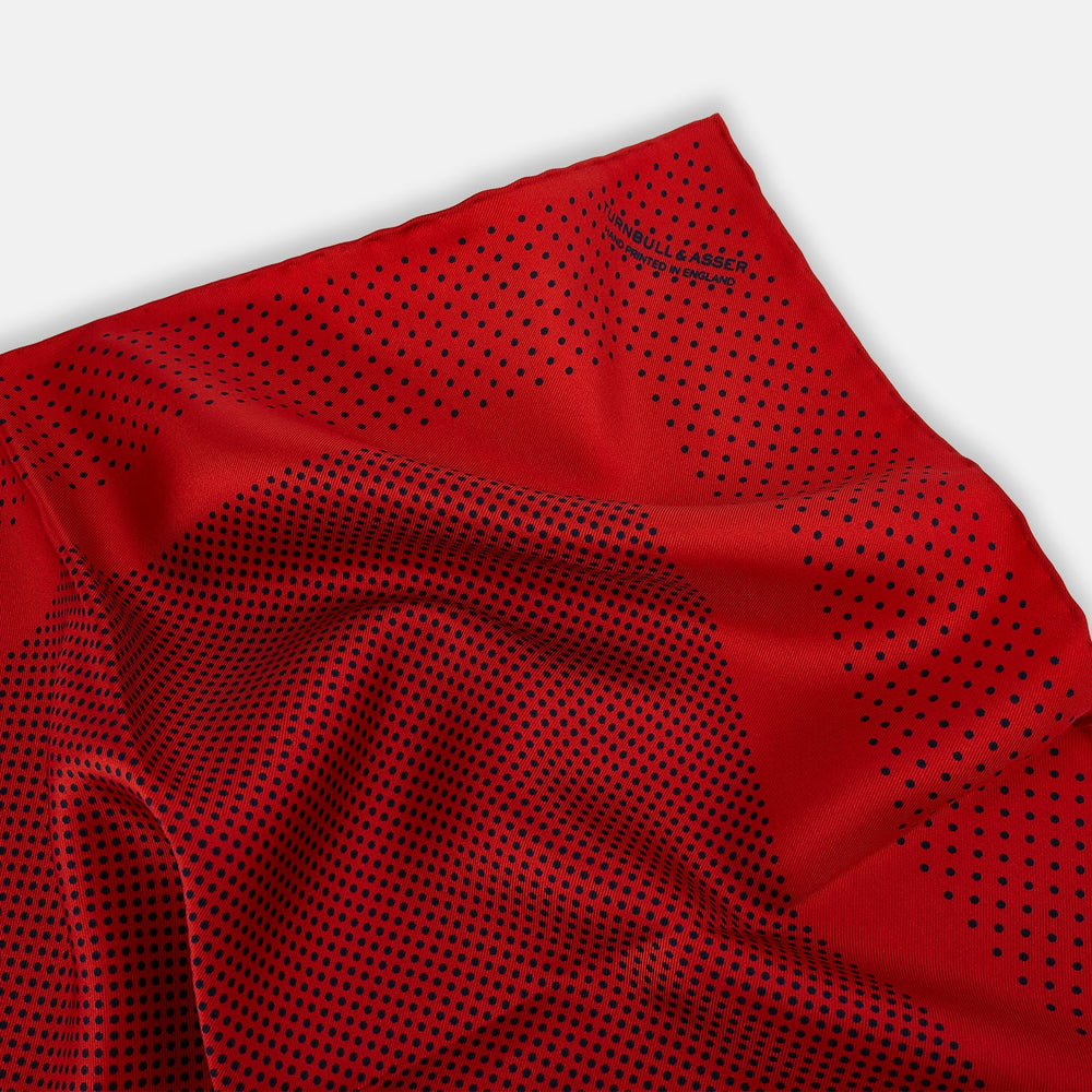The Turnbull & Asser Red Dot Silk Pocket Square showcases small black dots on red silk, neatly folded to reveal both the front and part of the reverse side.