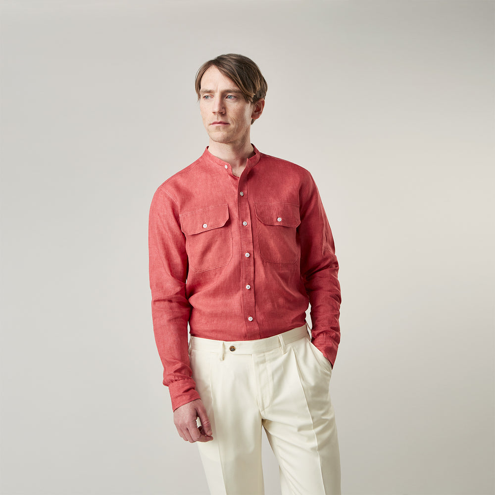 The Turnbull & Asser Plain Red Linen Weekend Fit Shirt with Stand Collar features long sleeves, a button-up front, and two buttoned-flap chest pockets. It is shown neatly laid flat on a plain light background.
