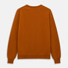 View 3 of product The Turnbull & Asser Rust Glenn Crew Neck Jumper is a plain, long-sleeved Scottish knitwear piece with ribbed cuffs and hem, shown laid flat on a white background.