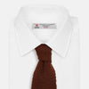 View 2 of product The Turnbull & Asser KNITTED BROWN SILK PLAIN TIE—a stylish, textured accessory—appears rolled up on a white background, perfect for elevating smart outfits.
