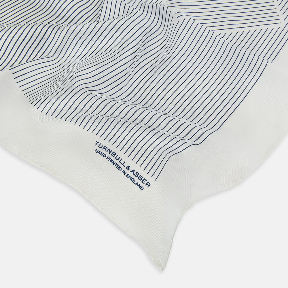 The White Stripe Silk Pocket Square by Turnbull & Asser features vertical navy pinstripes and “TURNBULL & ASSER HAND PRINTED IN ENGLAND” in blue at the lower right, with one corner neatly folded for a classic British look.