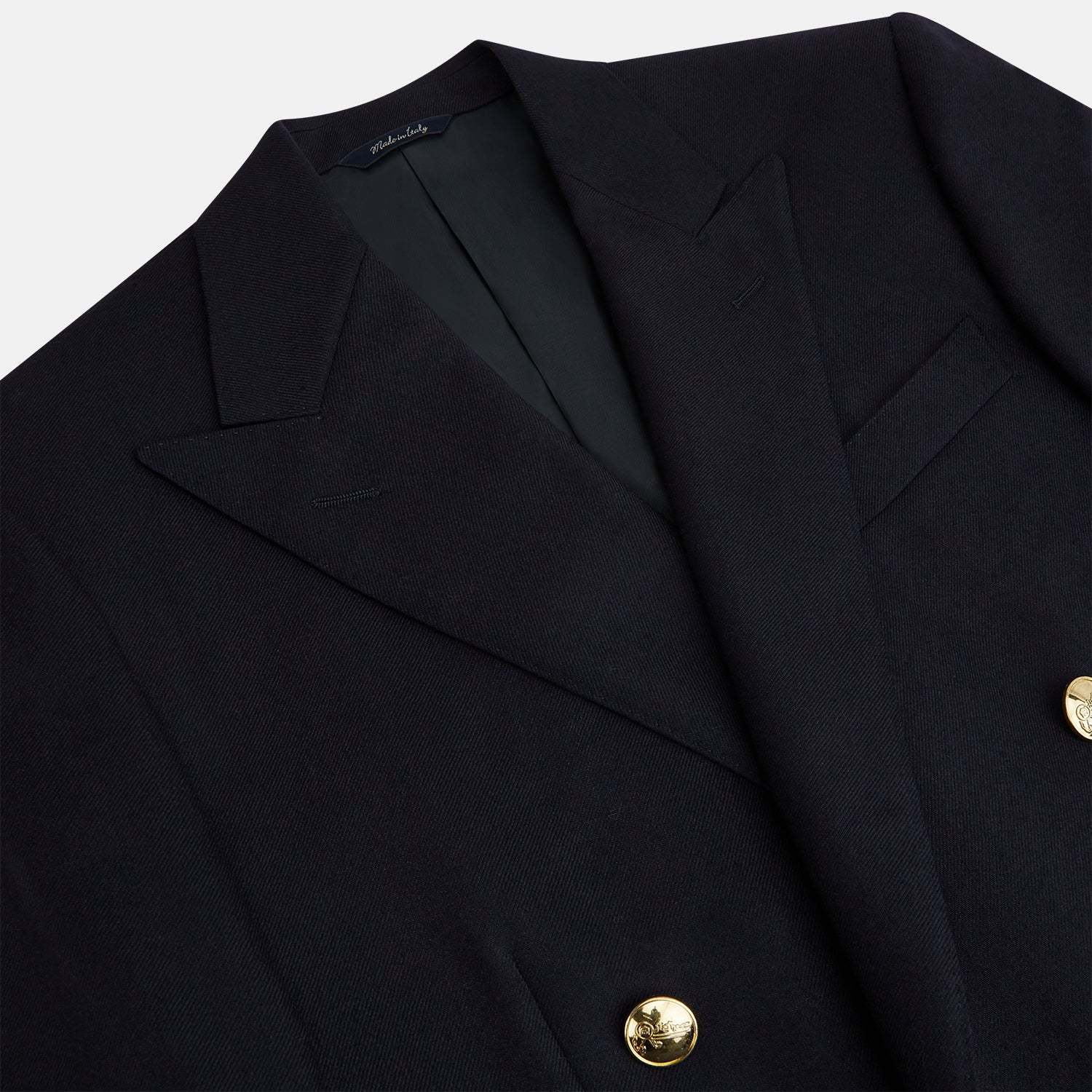 View 2 of product The Turnbull & Asser Long Navy Double Breasted Classic Blazer features peak lapels, six gold buttons, flap pockets, and a chest pocket—showcasing classic British tailoring against a plain light background.