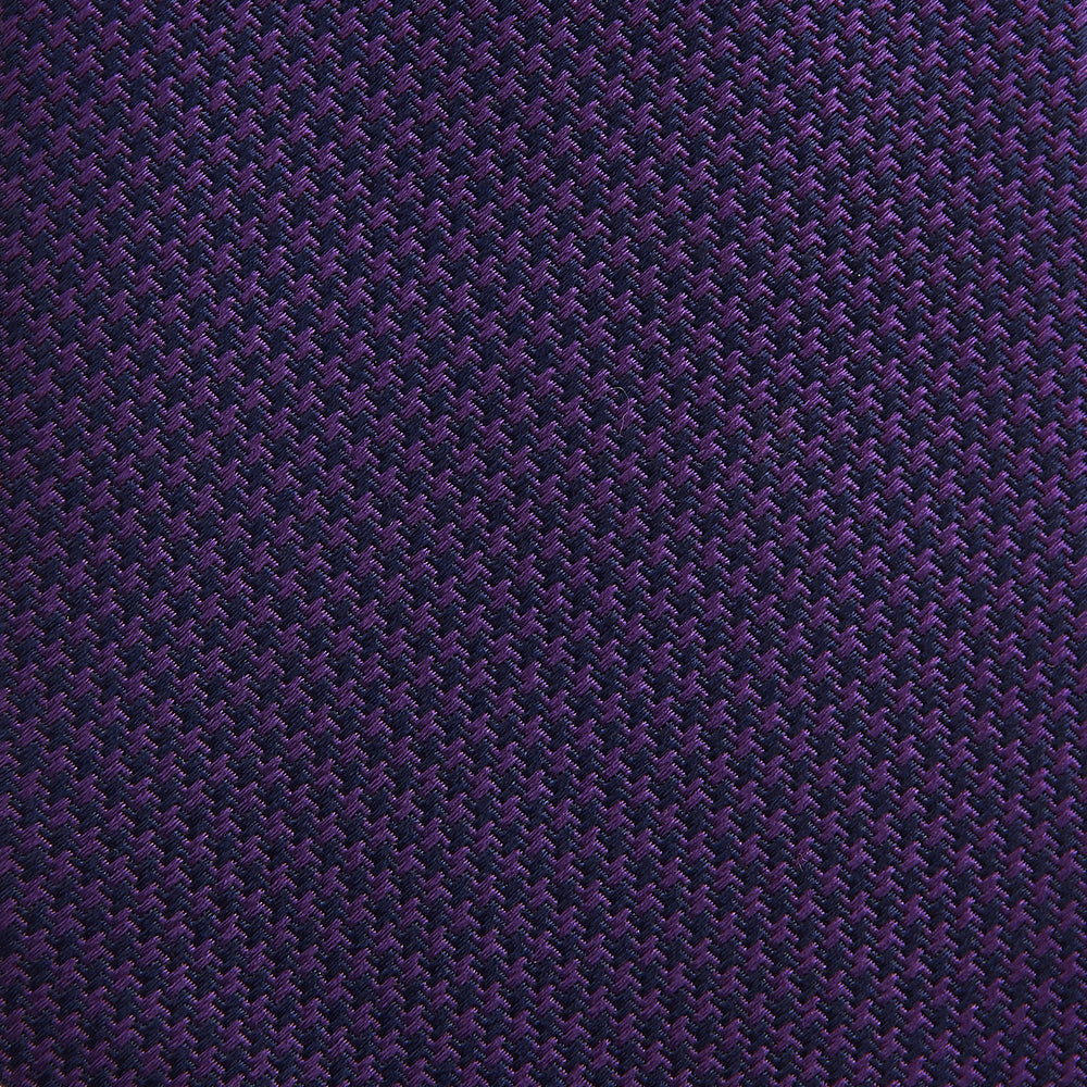 The HOUNDSTOOTH NAVY PLUM TIE by Turnbull & Asser, featuring a textured pattern, is showcased rolled up against a plain white background—an essential accessory.