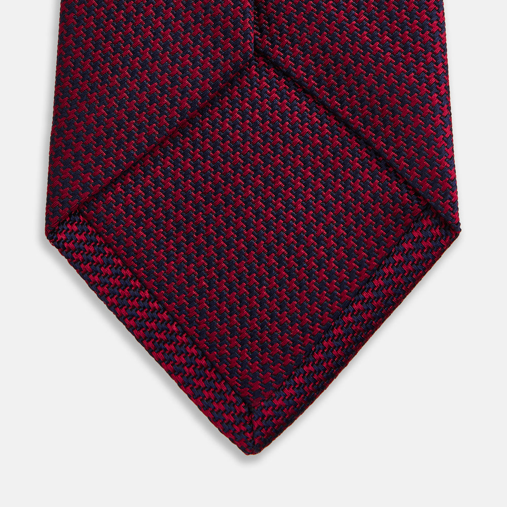The HOUNDSTOOTH NAVY BURGUNDY TIE by Turnbull & Asser features a textured navy and burgundy silk woven pattern—an elegant staple for every gentleman’s wardrobe.