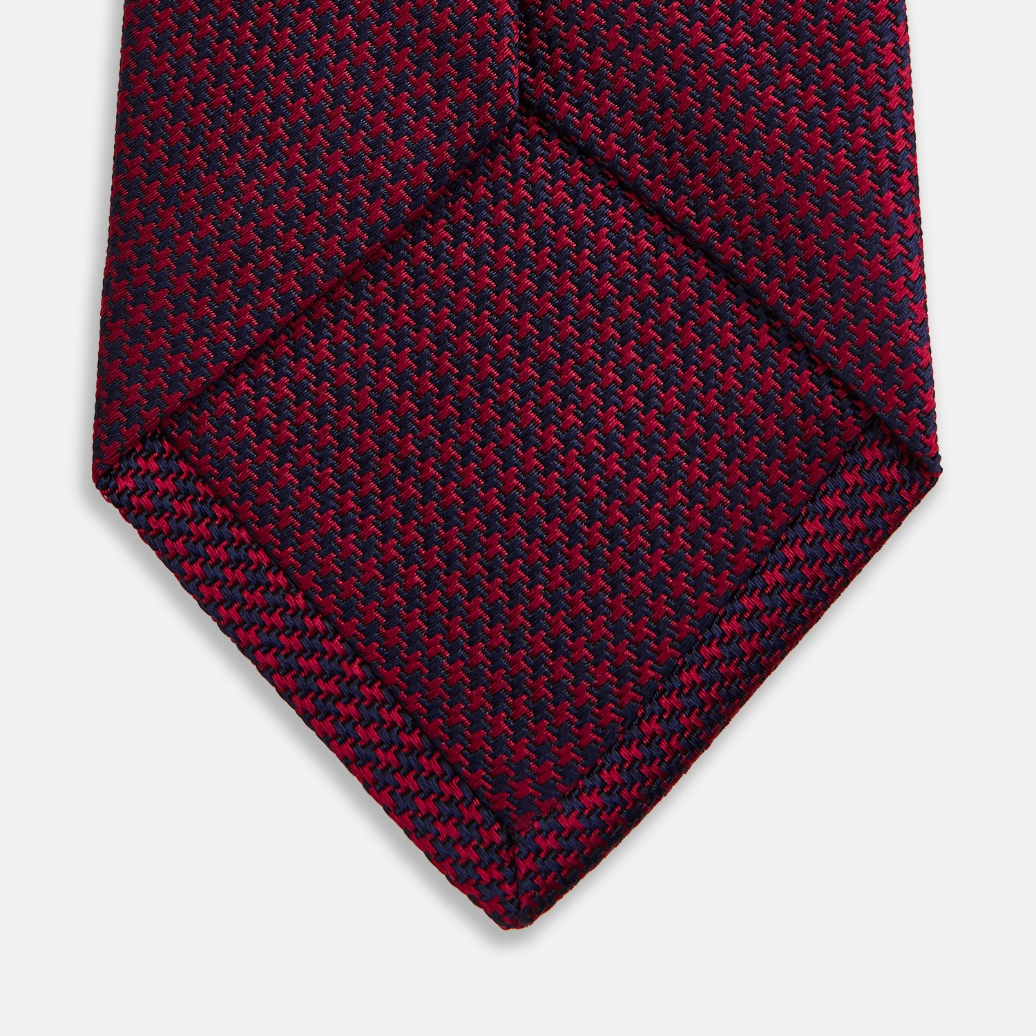 View 4 of product The HOUNDSTOOTH NAVY BURGUNDY TIE by Turnbull & Asser features a textured navy and burgundy silk woven pattern—an elegant staple for every gentleman’s wardrobe.