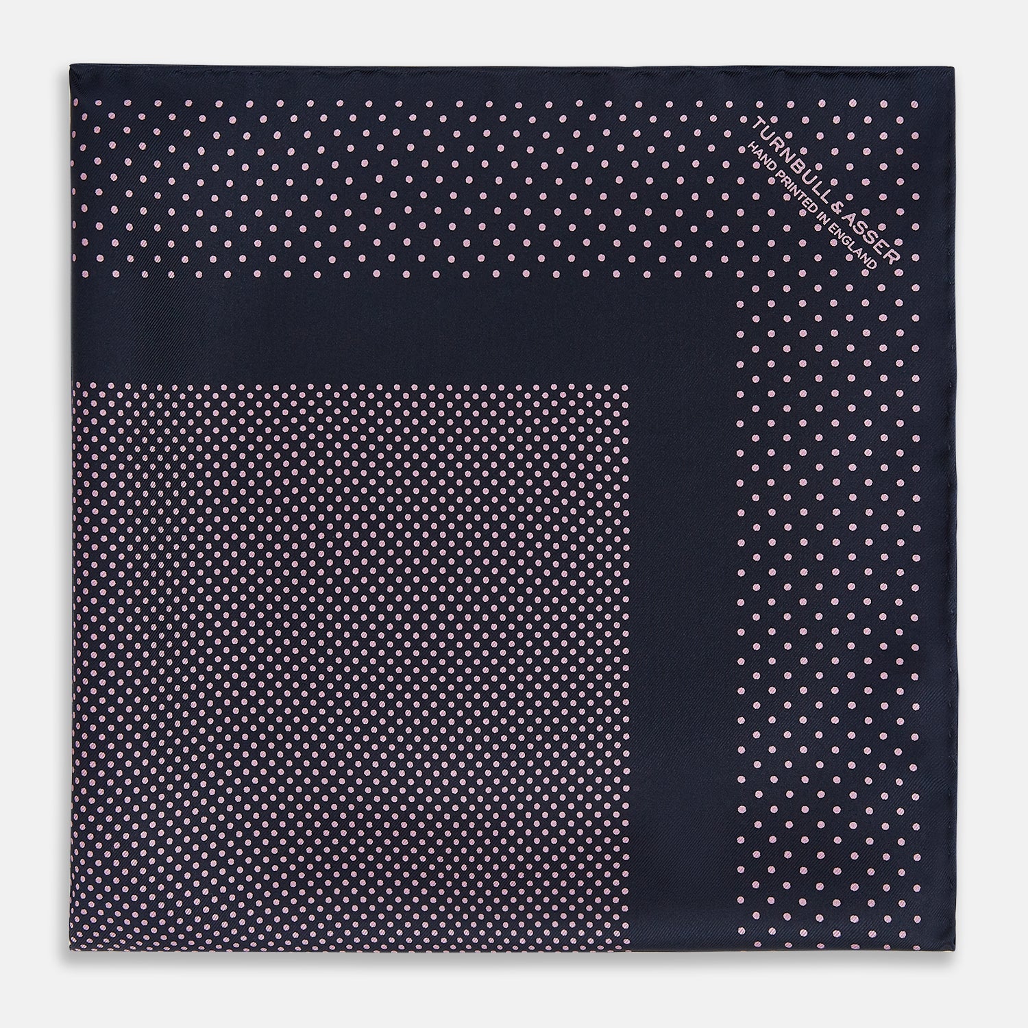 View 3 of product The Turnbull & Asser Navy and Pink Dot Silk Pocket Square features small pink dots and a solid border, with one corner folded to display both sides—an elegant accessory that reflects fine handmade craftsmanship.