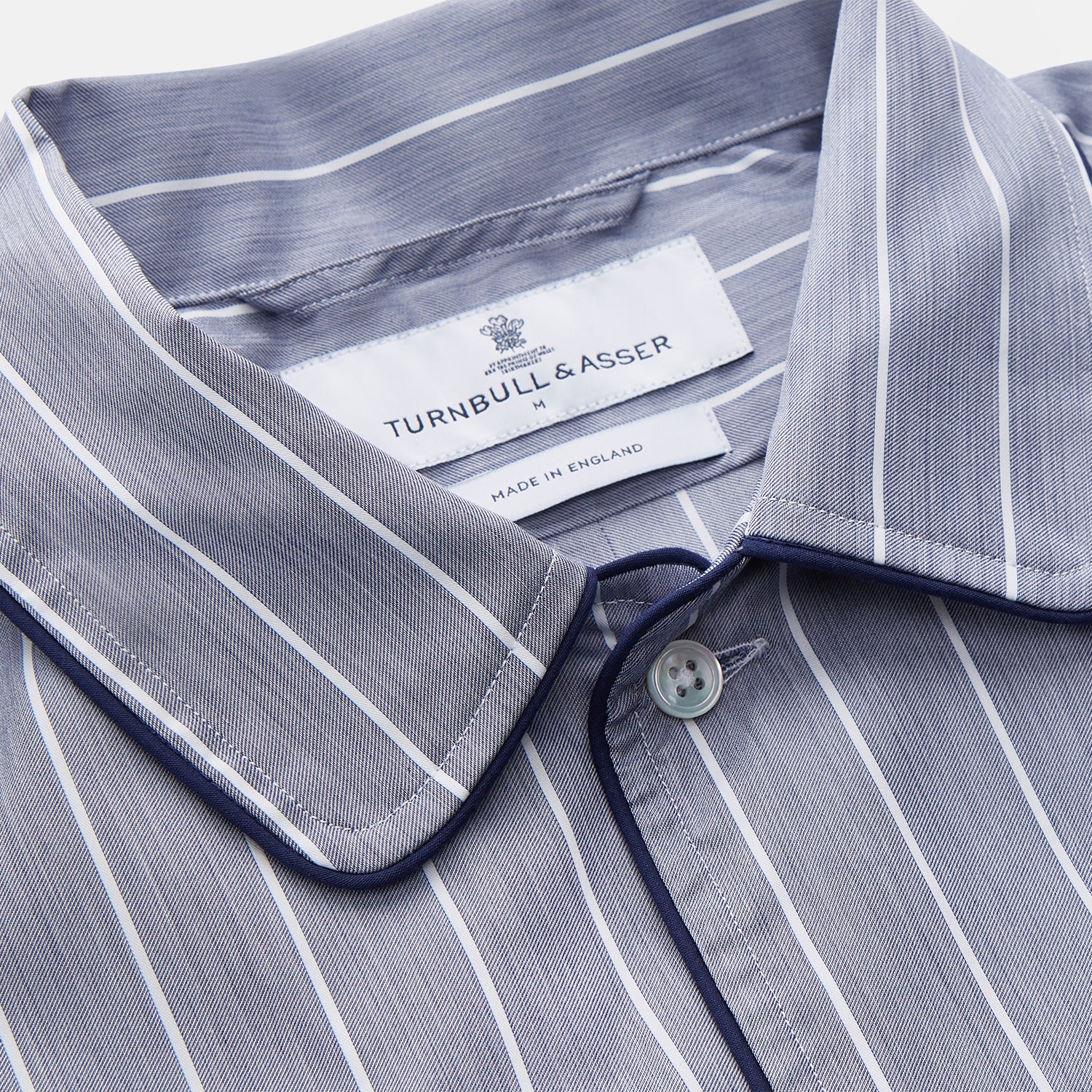 View 4 of product The Turnbull & Asser Pale Blue and White Pinstripe Cotton Blend Sussex Nightshirt pairs classic style with comfort, featuring long sleeves, a collar, front buttons, chest pocket, and curved hemline—perfect for luxury sleepwear.