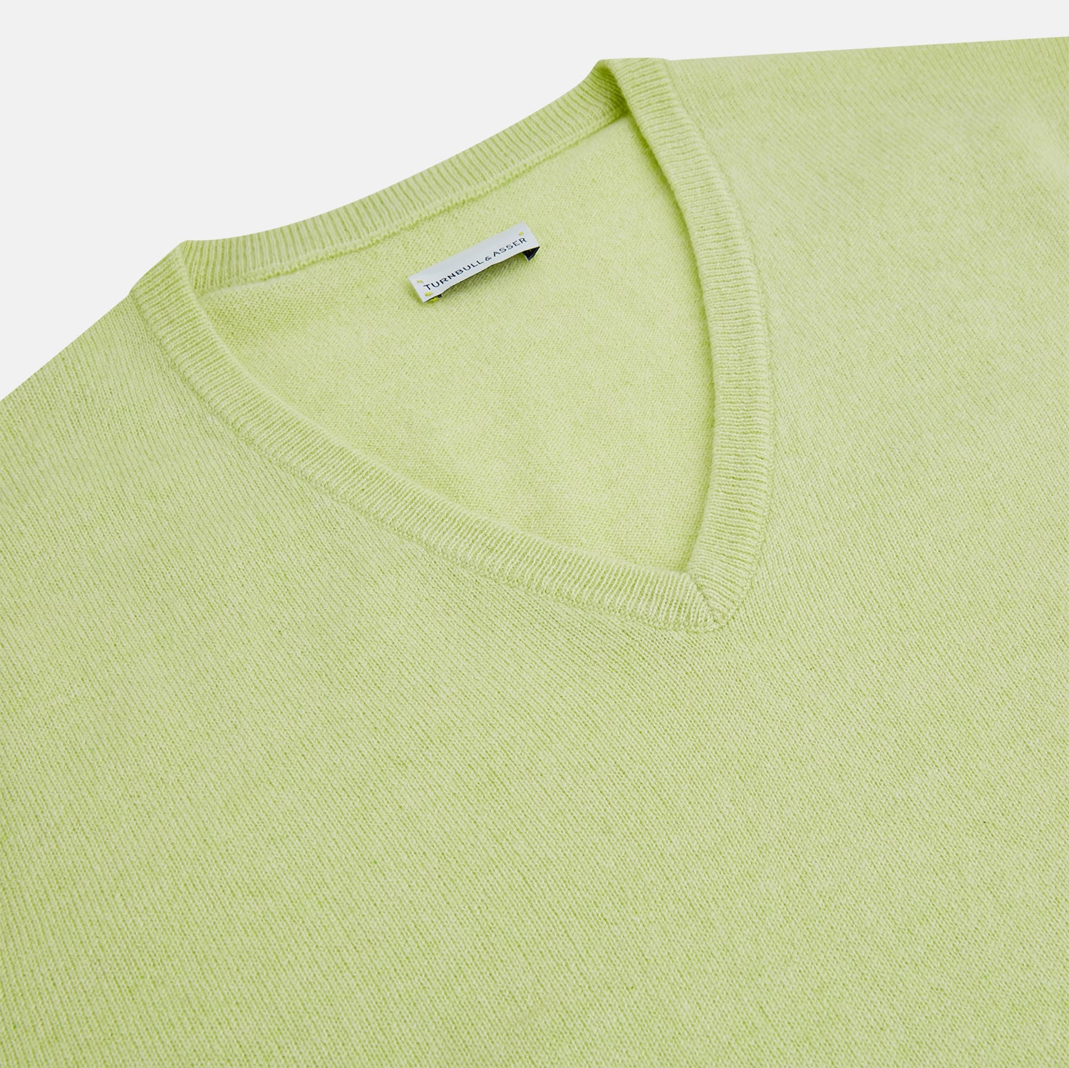 View 2 of product The Turnbull & Asser Pistachio Cashmere V-neck Jumper features long sleeves, ribbed cuffs and hem. Shown in light green against a white background, it's a classic addition to any knitwear collection.