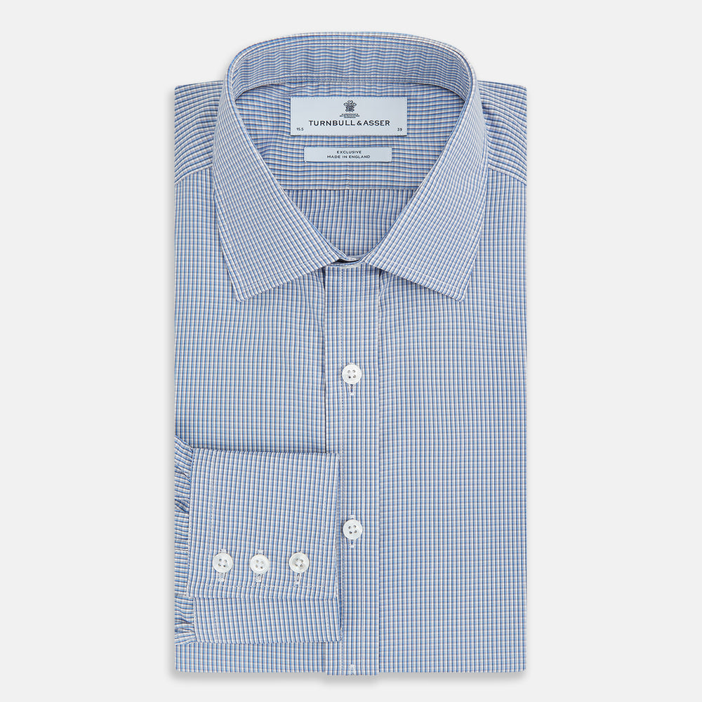 The Turnbull & Asser Pale Blue Micro Graph Check Mayfair Shirt features a small blue and white check pattern, classic T&A collar, white buttons, and buttoned cuffs. Presented on a plain white background.