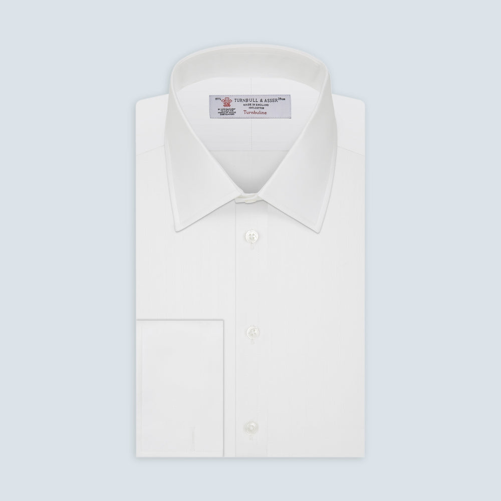 The Turnbull & Asser White Herringbone Superfine Cotton Shirt features a T&A collar, double cuffs, and a visible label inside the collar, shown neatly folded on a light blue background—ideal for minimalist looks or pairing with bold ties.