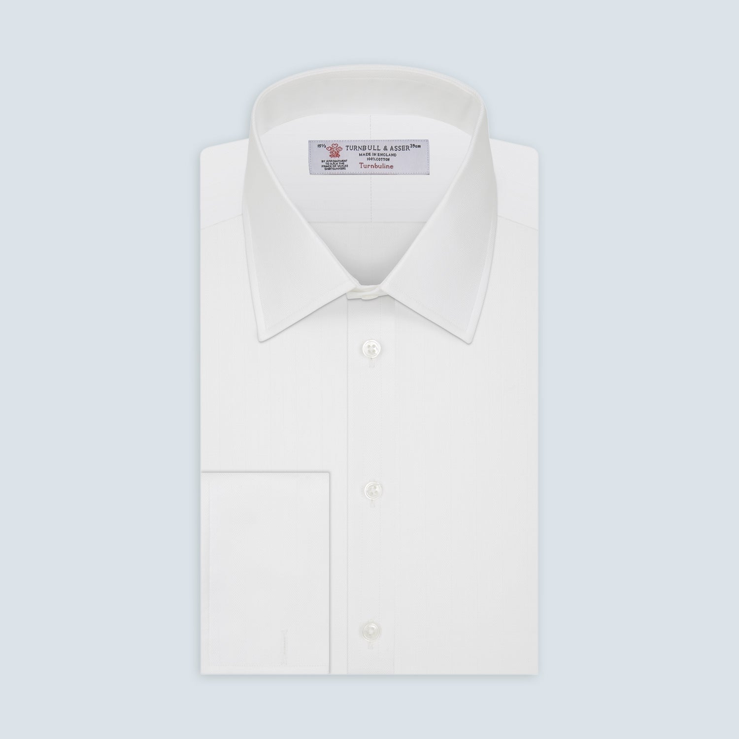 View 1 of product The Turnbull & Asser White Herringbone Superfine Cotton Shirt features a T&A collar, double cuffs, and a visible label inside the collar, shown neatly folded on a light blue background—ideal for minimalist looks or pairing with bold ties.