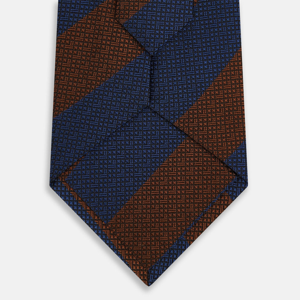 A close-up of the Turnbull & Asser Brown and Navy Block Stripe Silk Tie displays its textured pattern with classic suiting diagonal stripes in navy blue and brown on a light background.