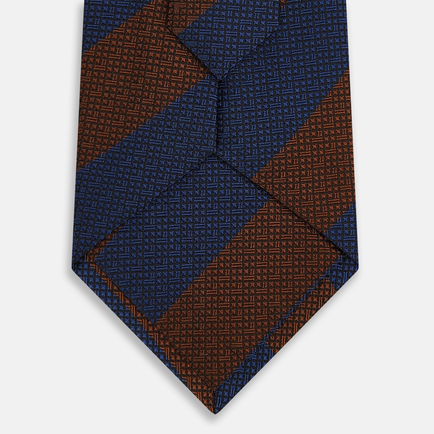 View 3 of product A close-up of the Turnbull & Asser Brown and Navy Block Stripe Silk Tie displays its textured pattern with classic suiting diagonal stripes in navy blue and brown on a light background.