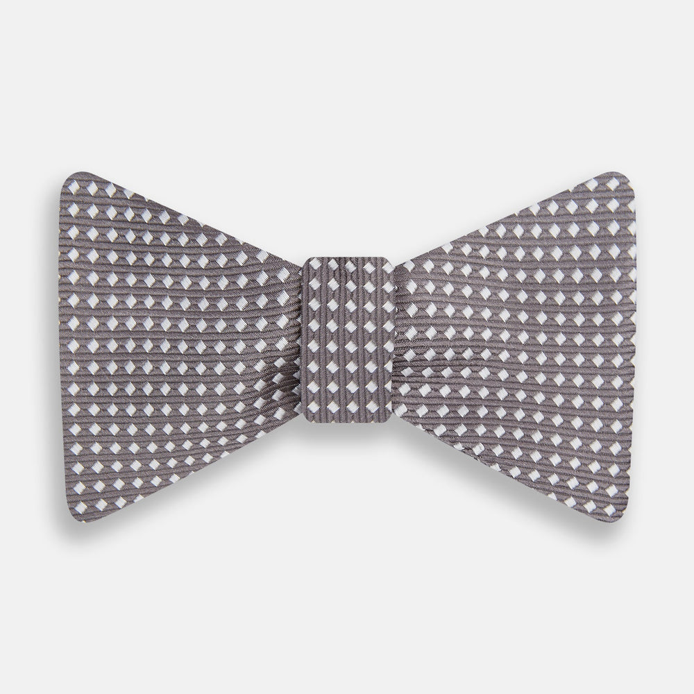 The Turnbull & Asser Grey and White Diamond Silk Bow Tie showcases a subtle diamond pattern, ideal for formalwear, and is elegantly displayed against a plain white background.