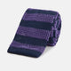 The KNITTED STRIPE PURPLE TIE by Turnbull & Asser features bold dark blue and purple stripes, making it an essential smart accessory. Shown rolled up on a white background.