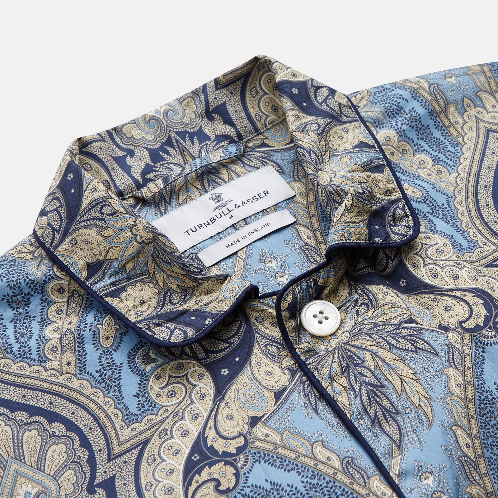 View 2 of product The Turnbull & Asser Pale Blue Baroque Silk-blend Hyde Pyjama Set features a long-sleeve button-up shirt and pants in a blue and beige paisley pattern, shown flat on a white background.