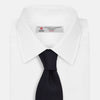 View 2 of product The GRENADINE NAVY TIE by Turnbull & Asser—a rolled, dark navy blue textured tie—serves as an essential accessory for smart outfits, shown against a plain white background.