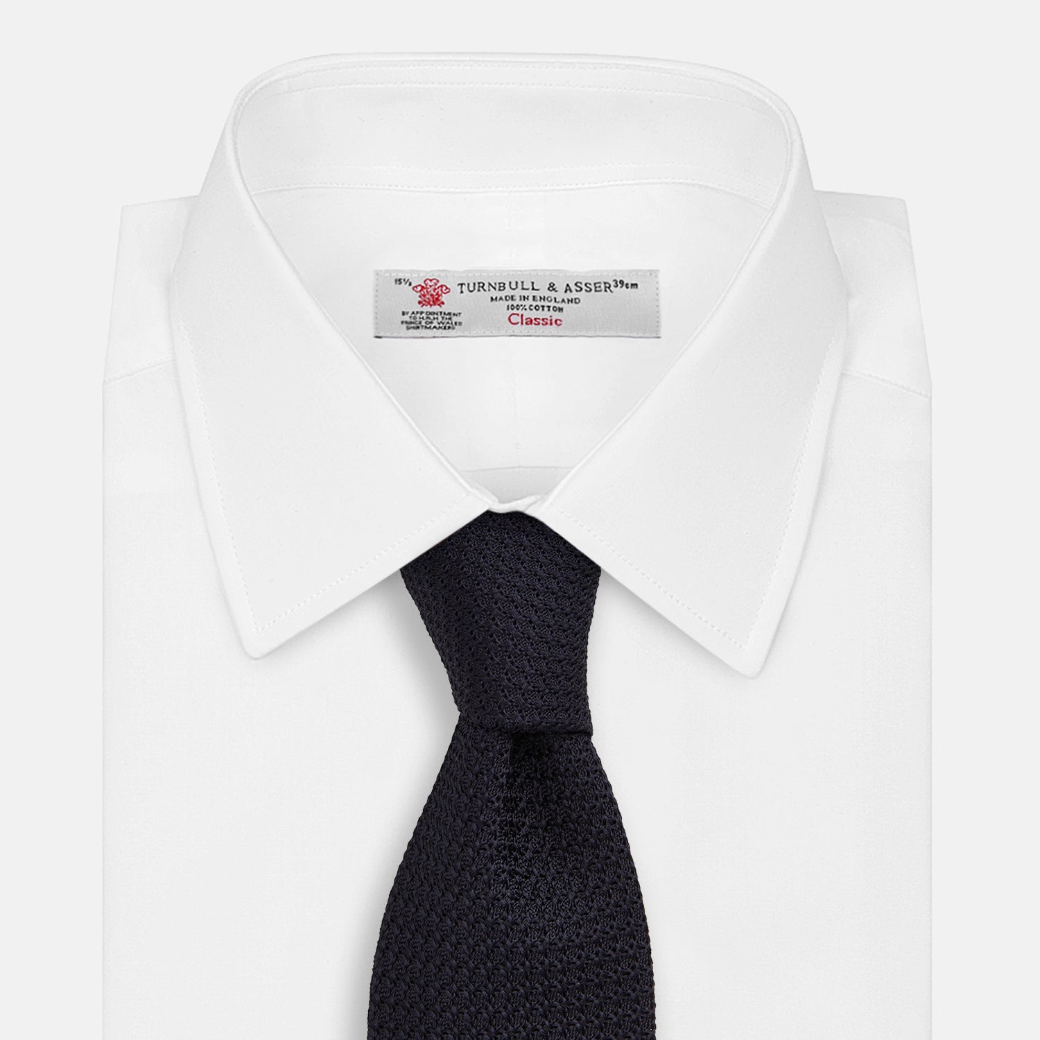 View 2 of product The GRENADINE NAVY TIE by Turnbull & Asser—a rolled, dark navy blue textured tie—serves as an essential accessory for smart outfits, shown against a plain white background.
