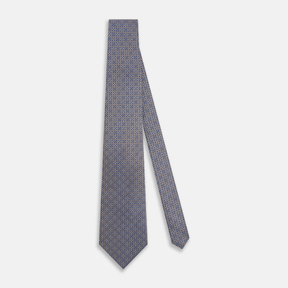 The Turnbull & Asser Silver and Pale Blue Multi Dot Silk Tie features elegant small dots on light brown silk, ideal for modern office wear, shown rolled up against a white background.