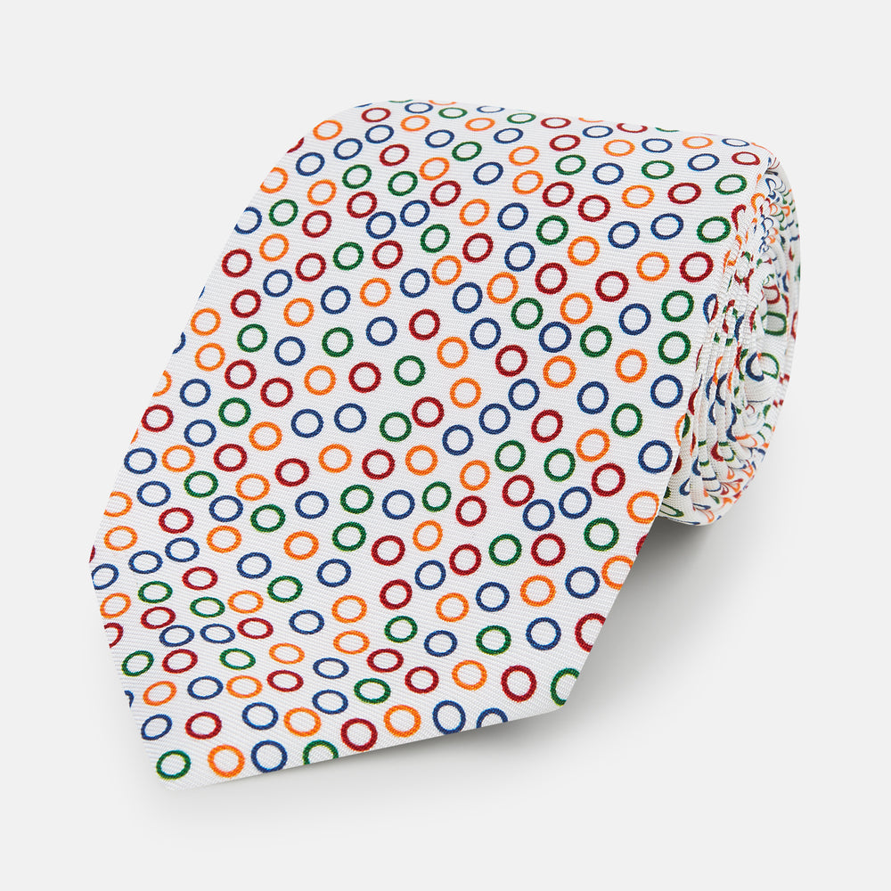 The Turnbull & Asser Confetti Circle White Silk Tie features colorful rings in red, orange, blue, and green scattered across a crisp white background.