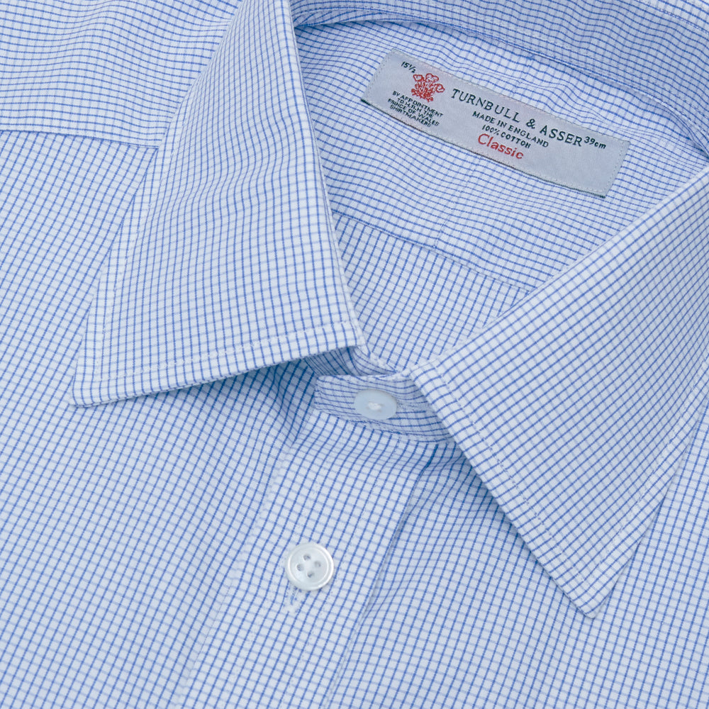 A neatly folded Turnbull & Asser Blue Grid Check Shirt features a T&A collar, 3-button cuffs, white buttons, and subtle British style. The blue and white check cotton design displays the brand label inside the collar.