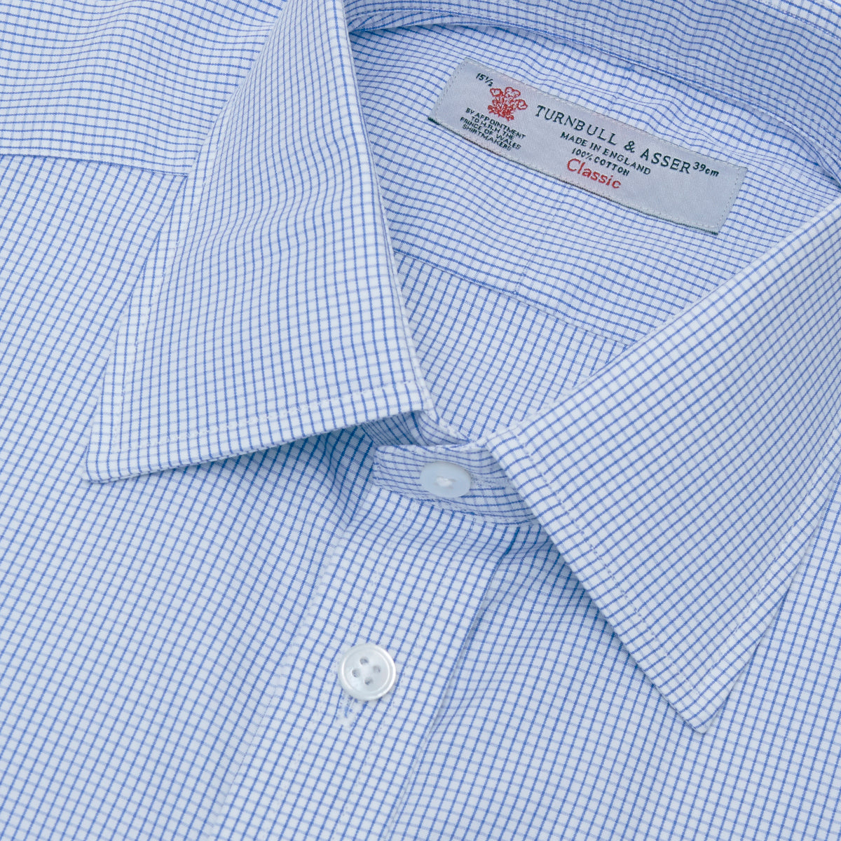 View 2 of product A neatly folded Turnbull & Asser Blue Grid Check Shirt features a T&A collar, 3-button cuffs, white buttons, and subtle British style. The blue and white check cotton design displays the brand label inside the collar.