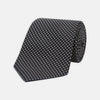View 1 of product The Turnbull & Asser Black and White Small Spot Printed Silk Tie, shown rolled against a white background, features a subtle polka dot pattern—an ideal accessory for any office shirt.