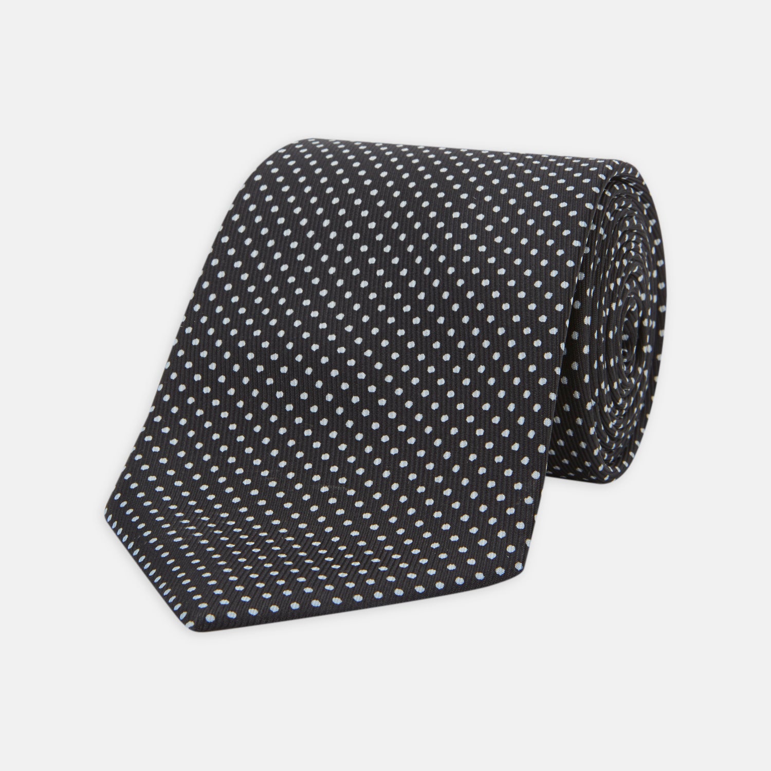 View 1 of product The Turnbull & Asser Black and White Small Spot Printed Silk Tie, shown rolled against a white background, features a subtle polka dot pattern—an ideal accessory for any office shirt.