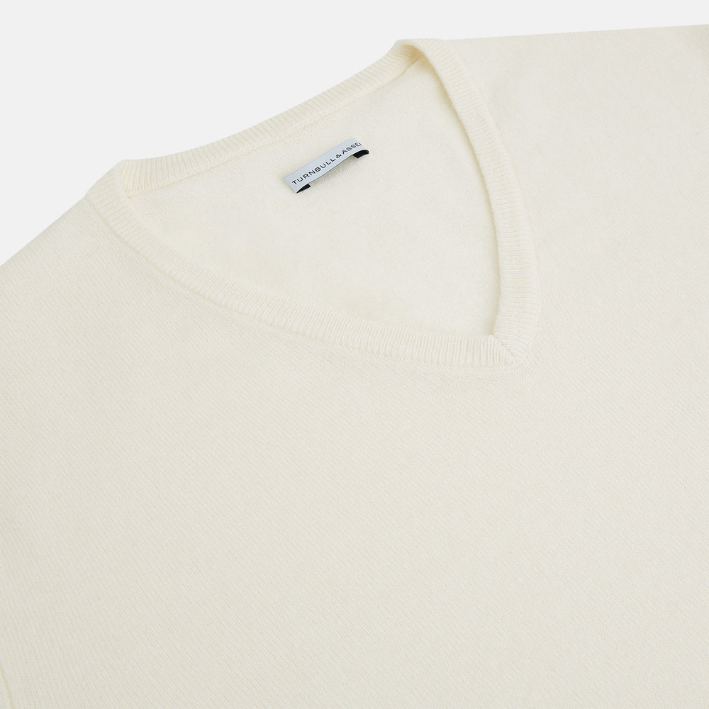 The Turnbull & Asser Ivory Cashmere V-neck Jumper features long sleeves with ribbed cuffs and hem, showcasing timeless knitwear style against a white background.
