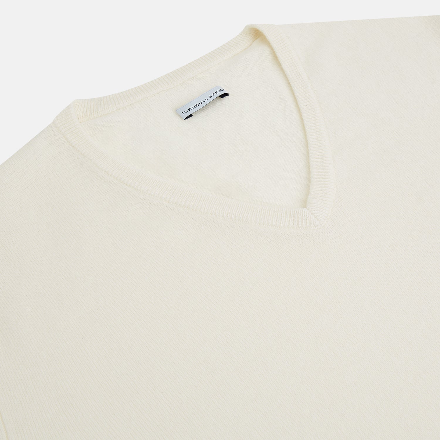 View 2 of product The Turnbull & Asser Ivory Cashmere V-neck Jumper features long sleeves with ribbed cuffs and hem, showcasing timeless knitwear style against a white background.