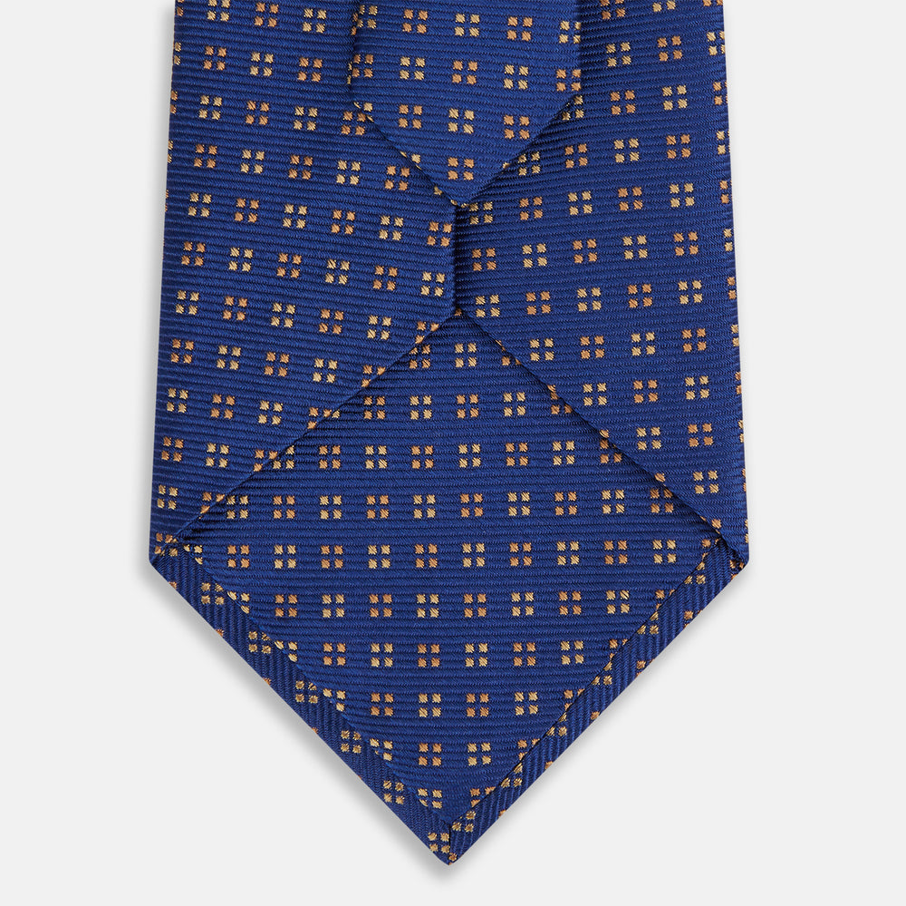 The Turnbull & Asser Bronze and Blue Multi Dot Silk Tie features a refined blue background with multicolored dots, elegantly displayed on a plain white backdrop—an ideal choice for a modern office look.