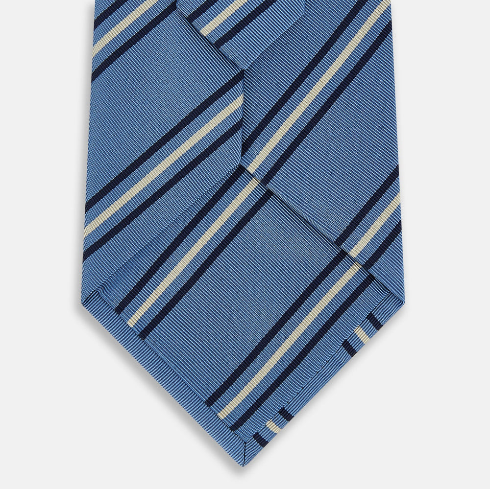 The Blue Multi Stripe Silk Blend Tie by Turnbull & Asser features diagonal navy and light beige stripes, shown rolled up on a white background—a timeless formal accessory.