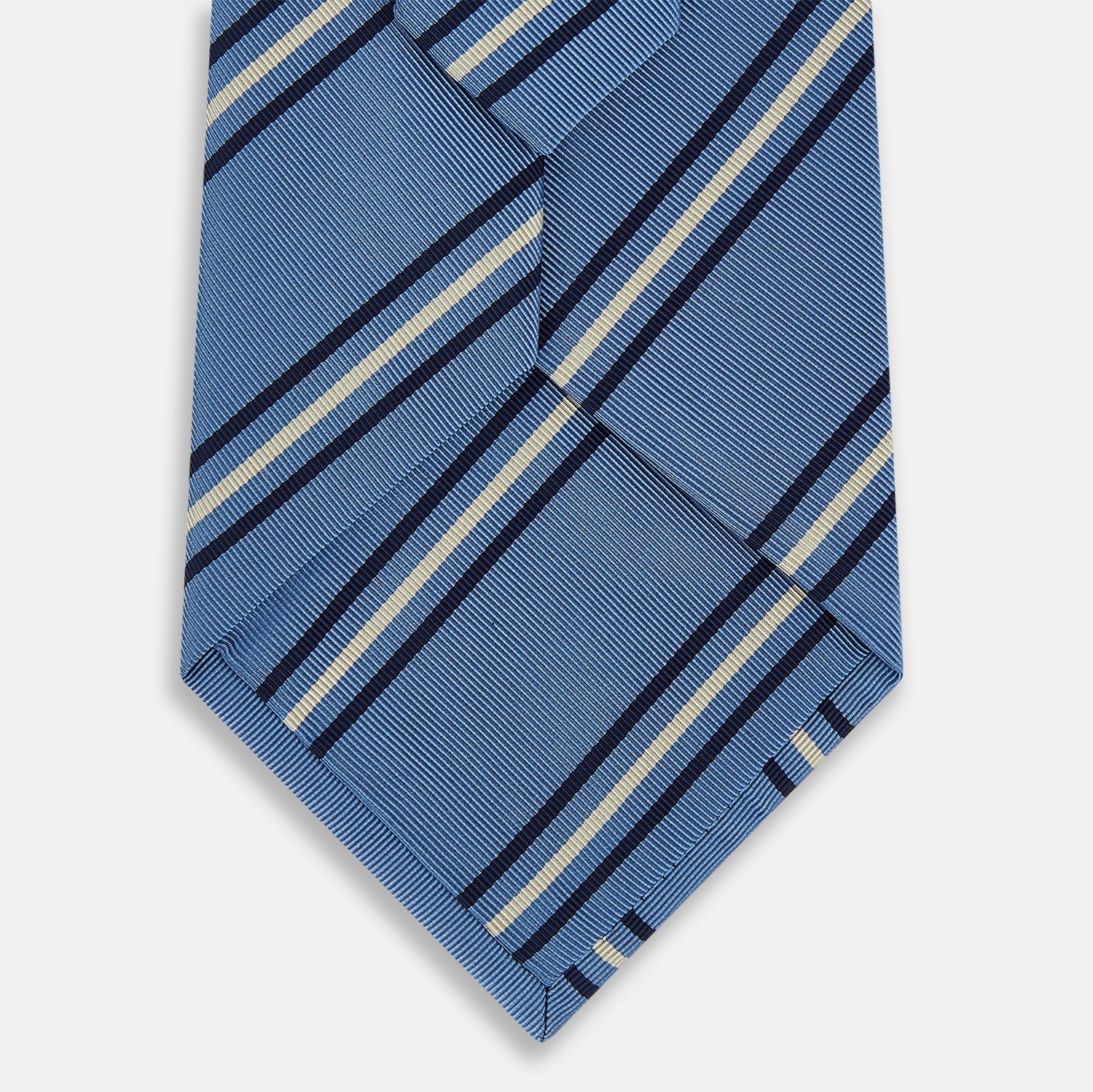 View 3 of product The Blue Multi Stripe Silk Blend Tie by Turnbull & Asser features diagonal navy and light beige stripes, shown rolled up on a white background—a timeless formal accessory.