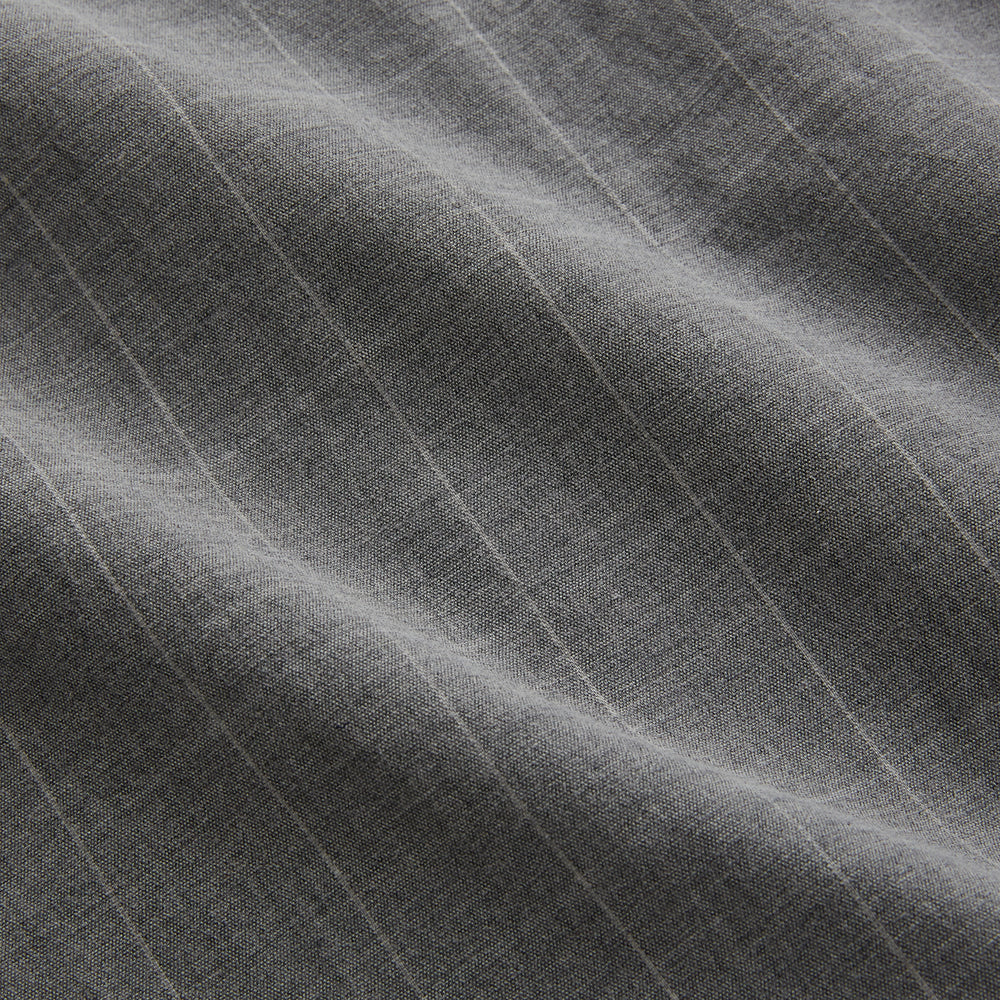 The Turnbull & Asser Grey Check Hampstead Overshirt features a light gray check pattern, pointed collar, chest pocket, and two zippered side pockets, displayed flat against a white background.