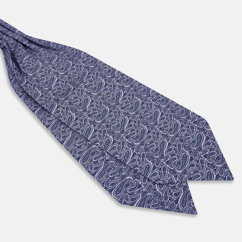 The Turnbull & Asser Lilac Paisley Silk Cravat showcases British elegance with its dark blue paisley pattern on a lilac background, beautifully displayed on a white surface.
