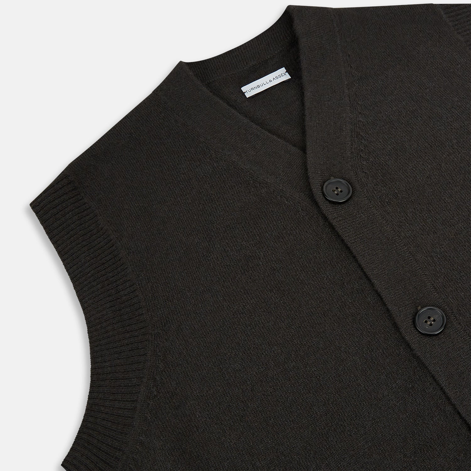 View 2 of product The Turnbull & Asser Dark Brown Cashmere Sleeveless Cardigan has a V-neck, button-up front, two front pockets, and ribbed trim on the armholes and hem, shown against a plain white background.