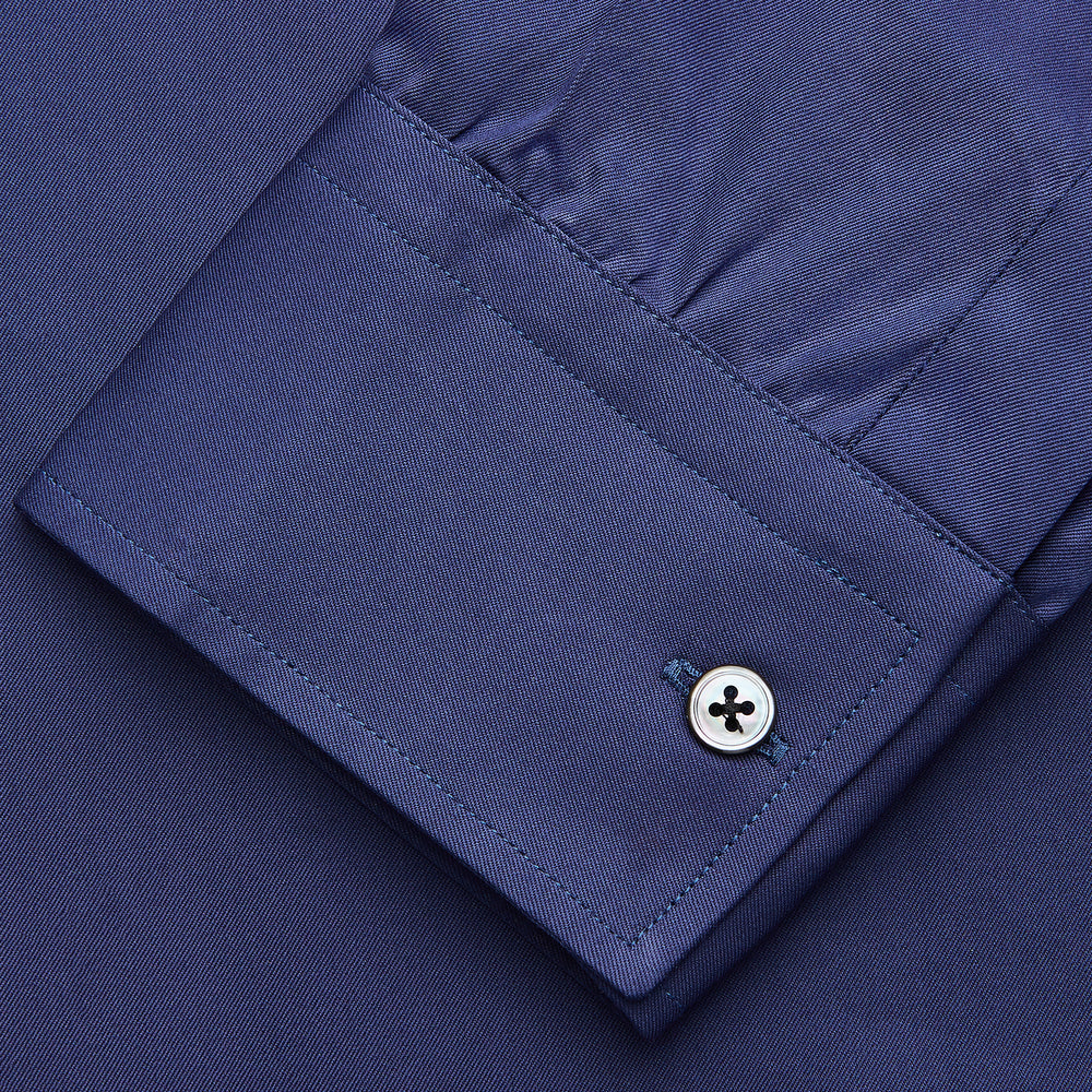 The Blue Piece Dyed Weekend Fit Suffolk Shirt by Turnbull & Asser features a button-down Dorset collar, chest pocket, white buttons, and long sleeves in classic navy, laid flat against a white background.