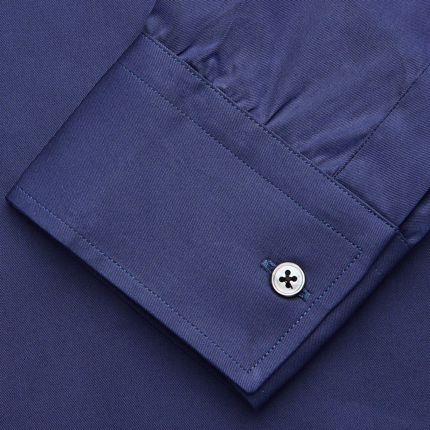 View 4 of product The Blue Piece Dyed Weekend Fit Suffolk Shirt by Turnbull & Asser features a button-down Dorset collar, chest pocket, white buttons, and long sleeves in classic navy, laid flat against a white background.