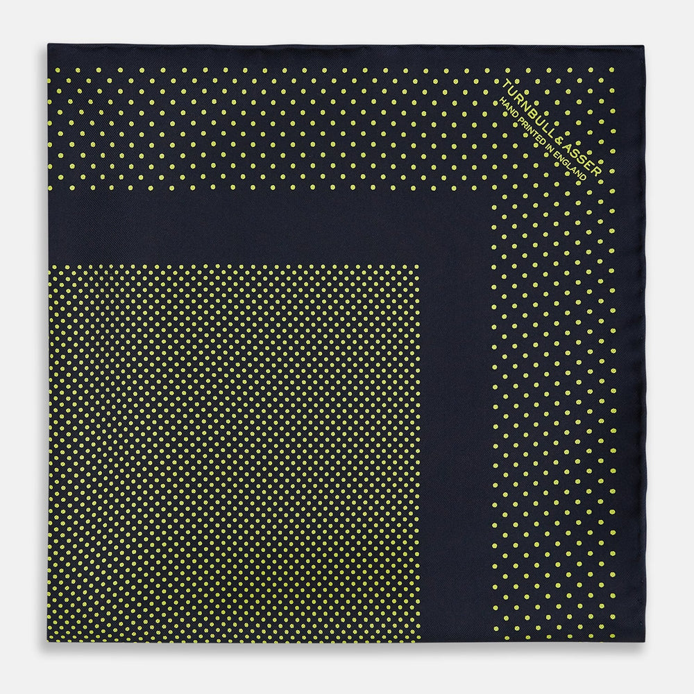 The Turnbull & Asser Navy and Yellow Dot Silk Pocket Square features a navy base with yellow dots, a solid navy border, and a folded corner showing the patterned underside for an elegant accent.