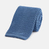 View 1 of product The Turnbull & Asser Knitted Mid Blue Silk Plain Tie features a textured knit and is shown rolled up on a plain white background—a refined accessory that pairs perfectly with formal shirts.