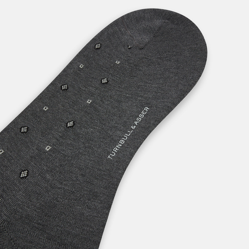 The Grey Patterned Mid-Length Socks by Turnbull & Asser are crafted from soft Egyptian cotton, with a ribbed cuff and small white diamond shapes on a grey background.