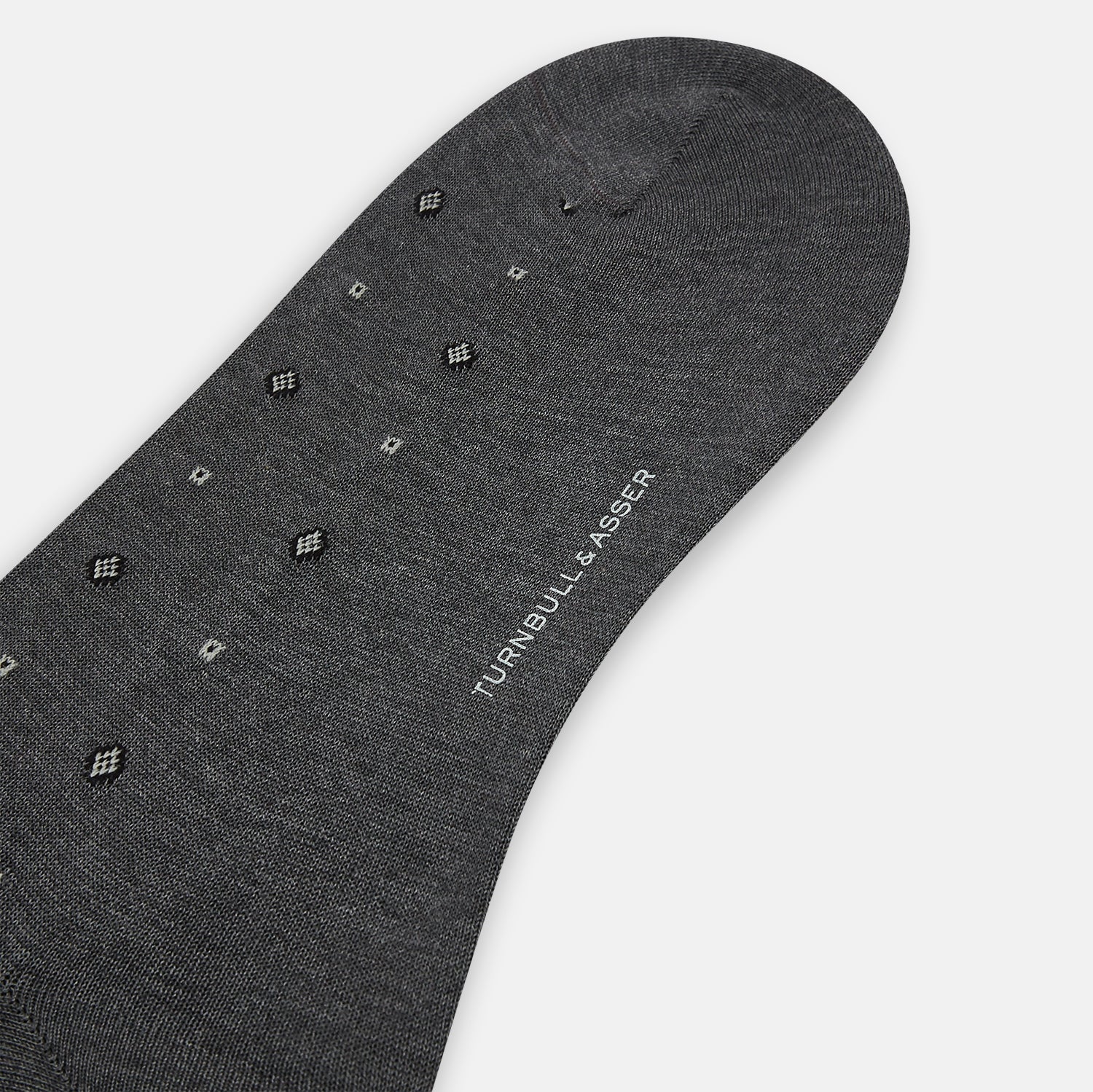 View 3 of product The Grey Patterned Mid-Length Socks by Turnbull & Asser are crafted from soft Egyptian cotton, with a ribbed cuff and small white diamond shapes on a grey background.