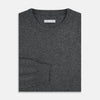 View 4 of product The Turnbull & Asser Charcoal Grey Cashmere Round Neck Jumper features a crew neck, long sleeves, and ribbed cuffs, collar, and hem—an essential piece of men’s knitwear displayed on a white background.