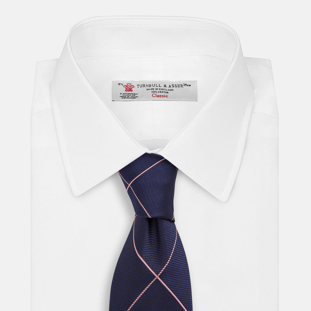 The Turnbull & Asser FONDANT PINK and WINDOW PANE NAVY Silk Tie features a subtle ribbed texture with a pink grid pattern on navy—an elegant choice for polished office attire, shown neatly rolled on a white background.