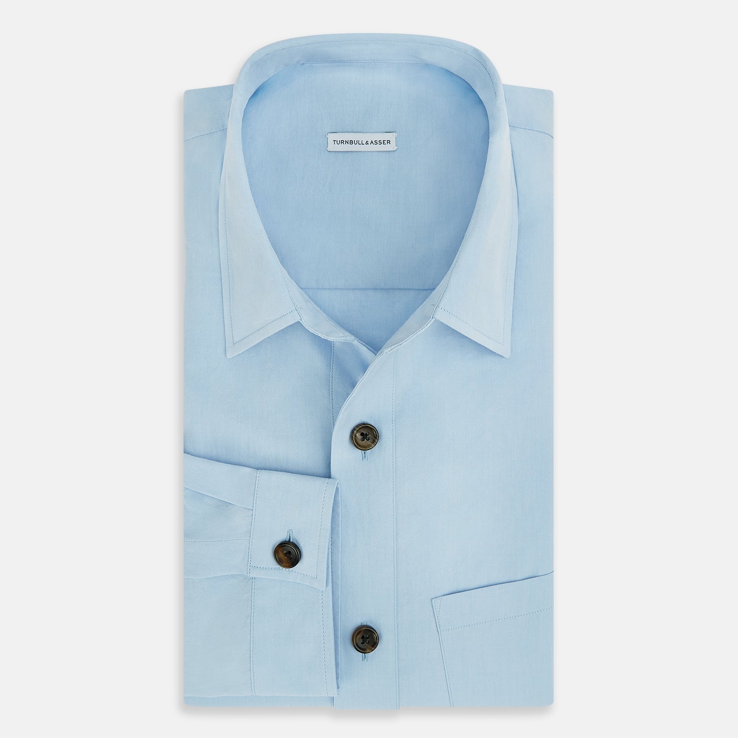 View 5 of product The Blue Hyde Overshirt by Turnbull & Asser features a light blue hue, long sleeves, a button-up front, and a single chest pocket. Crafted from sanforised cotton and shown laid flat on a white background.