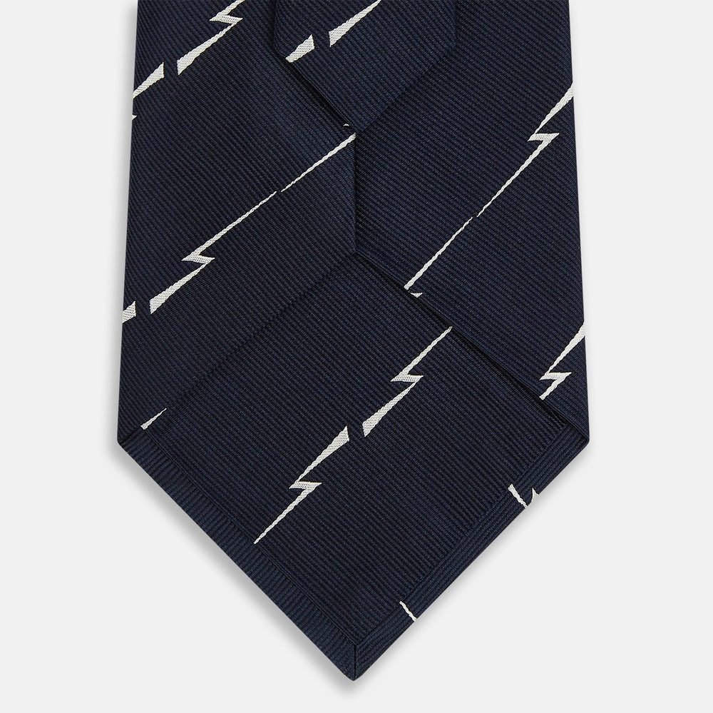 The Turnbull & Asser Navy Zigzag Jacquard Silk Tie is crafted from fine English silk, featuring a navy base with thin white zigzag stripes and shown rolled up on a plain white background.