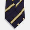 View 3 of product The Turnbull & Asser White and Navy Blazer Silk Tie, featuring diagonal yellow and white stripes, is rolled up neatly on a light gray background.