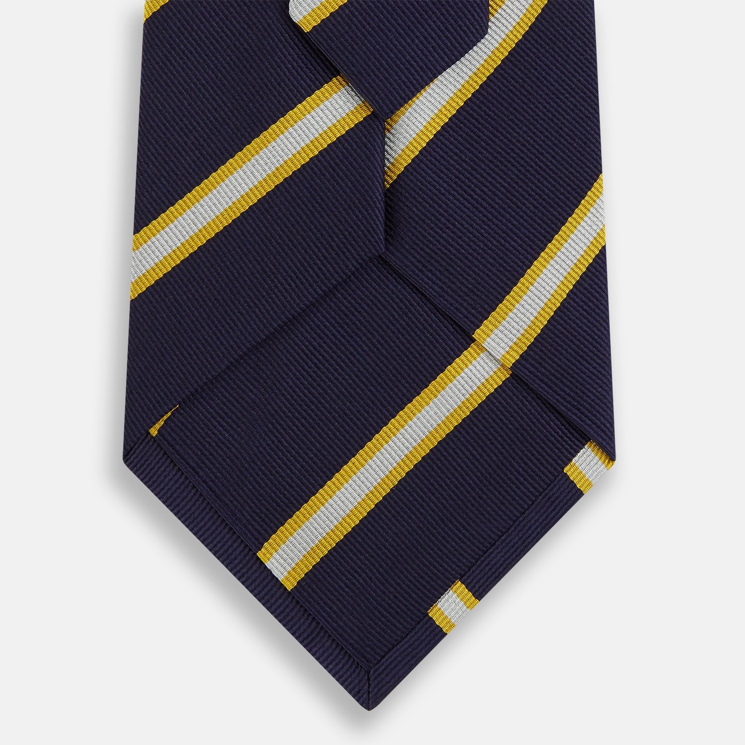 View 3 of product The Turnbull & Asser White and Navy Blazer Silk Tie, featuring diagonal yellow and white stripes, is rolled up neatly on a light gray background.