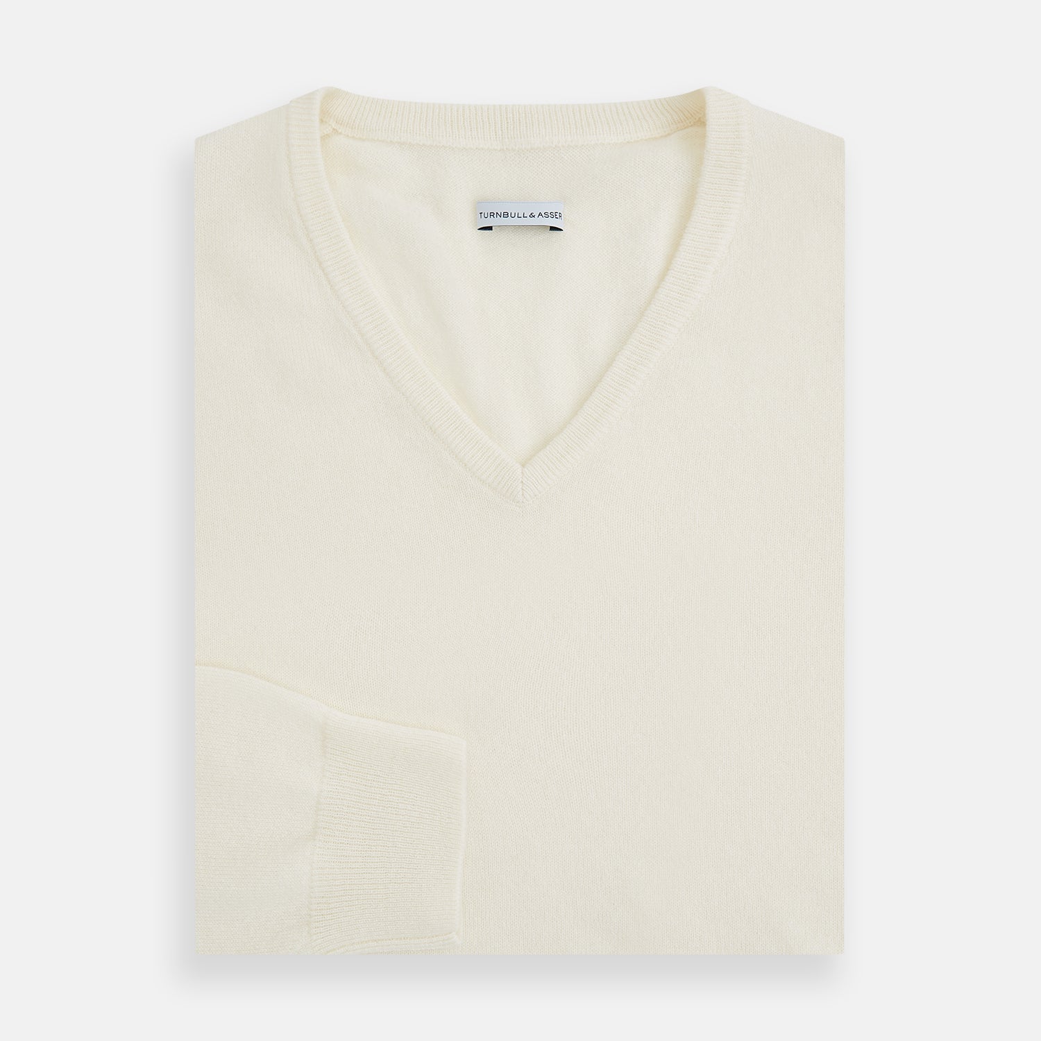 View 4 of product The Turnbull & Asser Ivory Cashmere V-neck Jumper features long sleeves with ribbed cuffs and hem, showcasing timeless knitwear style against a white background.
