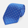 View 1 of product The Turnbull & Asser Blue and White Micro Dot Silk Tie features a subtle herringbone pattern with small white dots, ideal for modern office attire, and is shown rolled up on a white background.